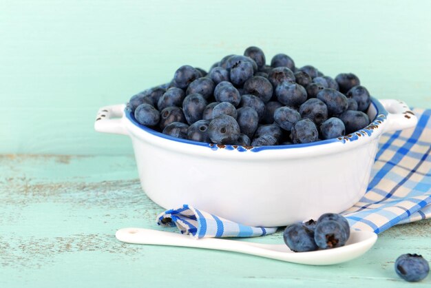 Leckere reife Blaubeeren in der Schüssel auf Holztisch