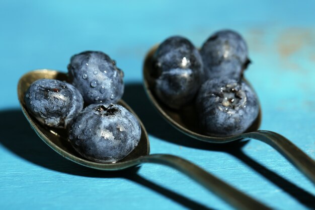 Leckere reife Blaubeeren in Löffeln auf Holztisch