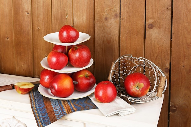 Leckere reife Äpfel auf Serviertablett auf Holzhintergrund