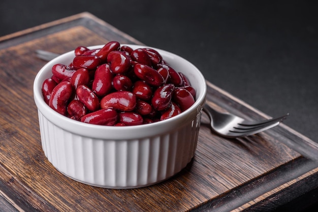 Leckere rote Bohnen aus der Dose in einer schönen weißen Schüssel auf einem Holzbrett