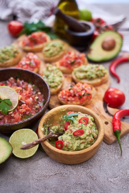 Leckere Salsa- und Guacamole-Bruschetta-Snacks in der heimischen Küche auf Holzschneidebrett