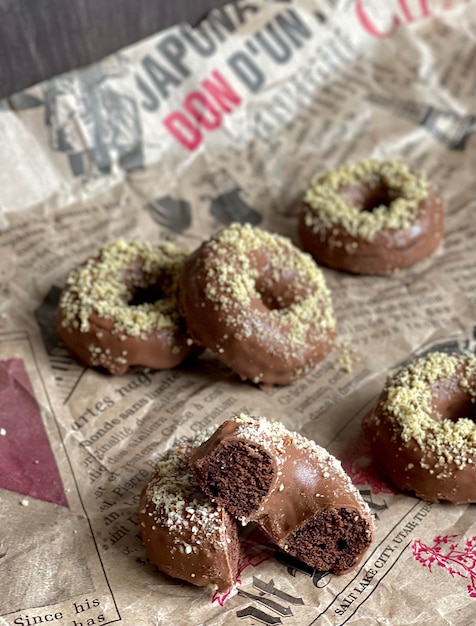 leckere schokoladengebackene donuts mit nüssen auf zeitung, donuts mit schokolade