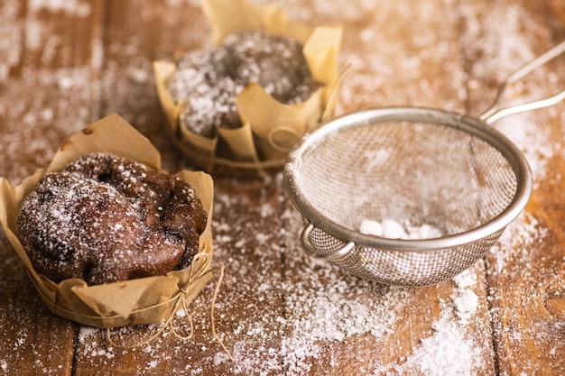 Leckere Schokoladenmuffins in Puderzucker auf dem Tisch