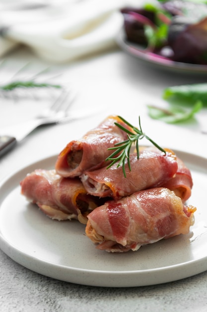 Leckere Schweine in Decken, in Speck gewickeltes Fleisch, hausgemachte gekochte Fleischbissen. Helles Essensfoto.