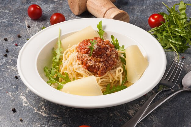 Leckere Spaghetti Bolognese auf einem weißen Teller mit Parmesan und Rucola. Horizontaler Rahmen