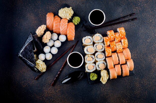 Leckere Sushi-Rollen auf Steinplatte mit Saucen