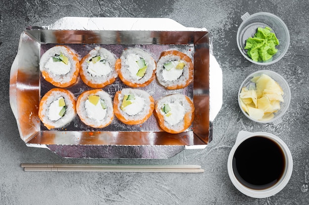 Leckere Sushi-Rollen in Einwegboxen auf grauem Stein