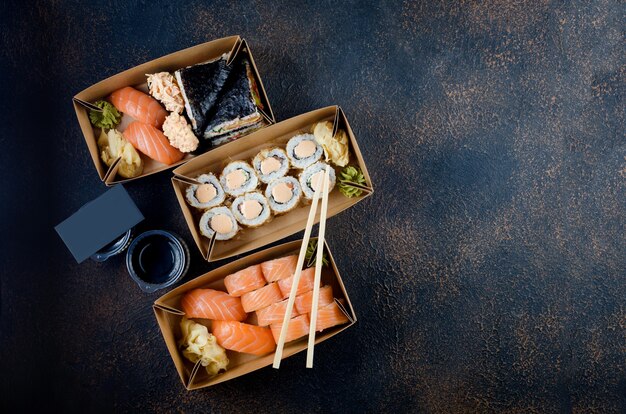 Leckere Sushi-Rollen mit Saucen, Essstäbchen und Ingwer auf dem Tisch