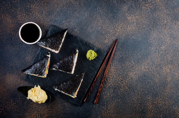 Leckere Sushi-Rollen mit Saucen, Essstäbchen und Ingwer auf dem Tisch