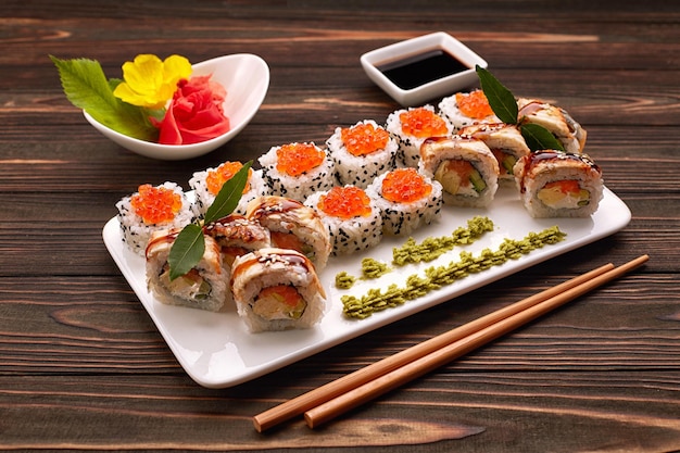 Leckere Sushi-Rollen mit Wasabi und Ingwer mit Essstäbchen