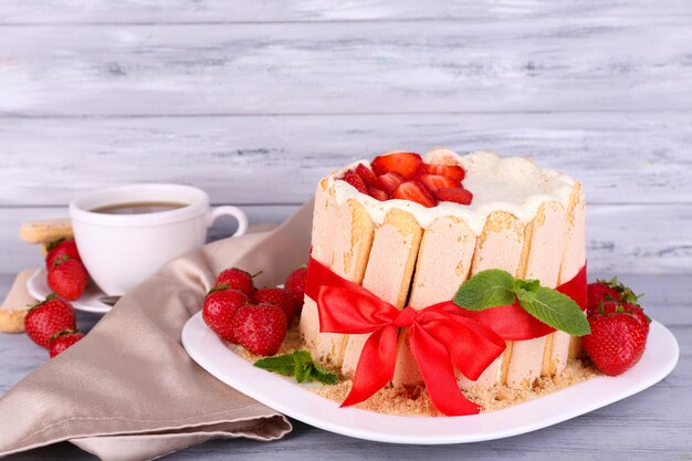 Leckere Torte Charlotte mit frischen Erdbeeren auf Holztisch