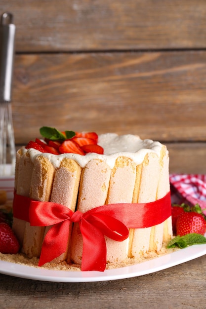 Leckere Torte Charlotte mit frischen Erdbeeren auf Holztisch