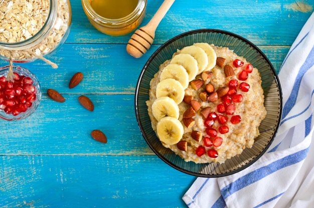 Leckere und gesunde Haferflocken mit Banane, Granatapfelkernen, Mandel und Zimt. Gesundes Frühstück. Fitness-Essen. Richtige Ernährung. Flach liegen. Ansicht von oben.