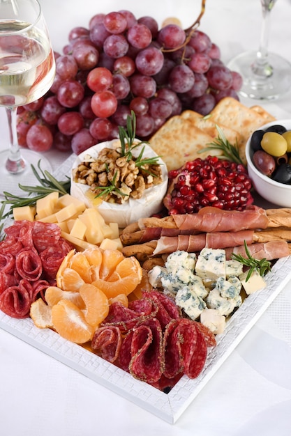 Leckere Vorspeisenplatte mit Salami und Käse, Grissini umhüllt von Parmaschinken, Oliven und Zitrusfrüchten. Eine originelle Antipasti für eine Party.
