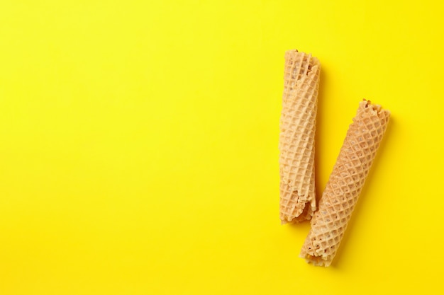 Leckere Waffelröllchen mit Kondensmilch auf gelb