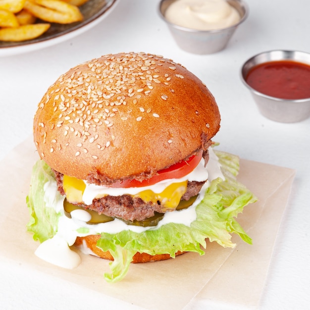 Leckerer Burger mit Pommes Frites, weißer Soße und Ketchup lokalisiert auf einem weißen Hintergrund. Konzept: Foto für Menü.