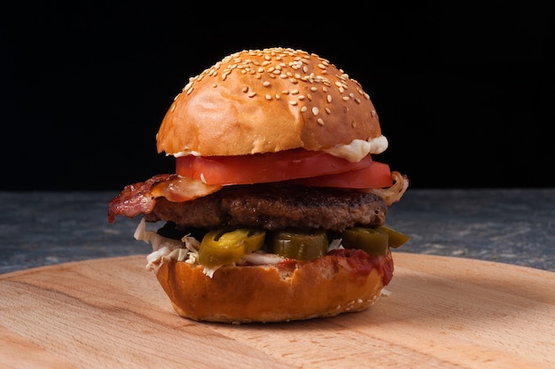 Leckerer Burger mit Rindfleisch, Speck und Jalapeno auf einem schwarzen Hintergrund