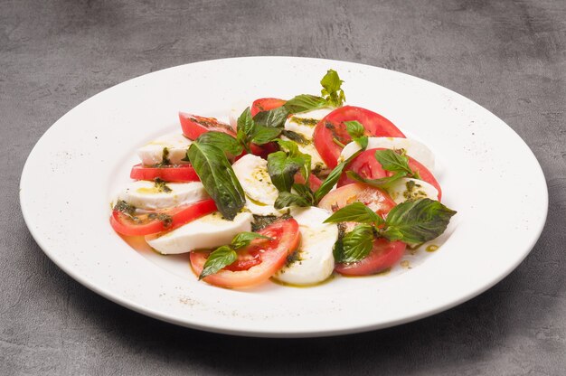 Leckerer Caprese-Salat mit Tomaten und Mozzarella auf einem weißen Teller