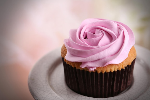 Leckerer Cupcake auf Ständer auf hellem Hintergrund