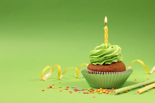 Leckerer Cupcake mit einer Kerze auf farbigem Hintergrund mit Platz zum Einfügen von Text