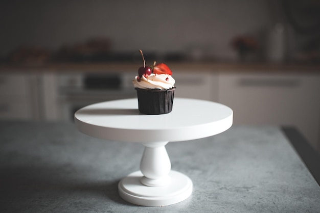 Leckerer Cupcake mit Früchten auf weißem Tablett bleibt auf dem Küchentisch