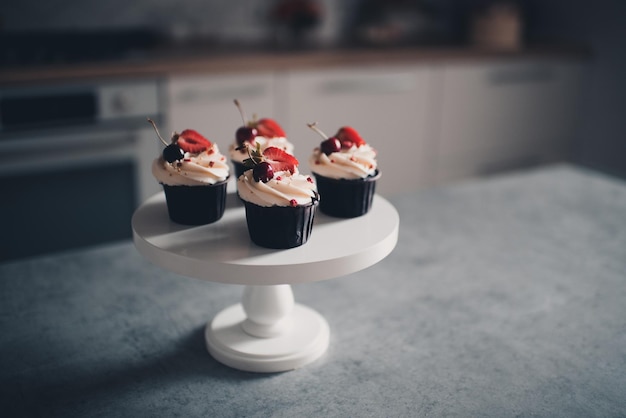 Leckerer Cupcake mit Früchten auf weißem Tablett bleibt auf dem Küchentisch