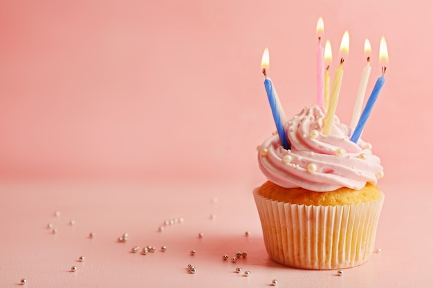 Leckerer Cupcake mit Kerze auf rosa verziert