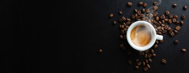 Leckerer dampfender Espresso in einer Tasse mit Kaffeebohnen. Von oben betrachten. Dunkler Hintergrund.