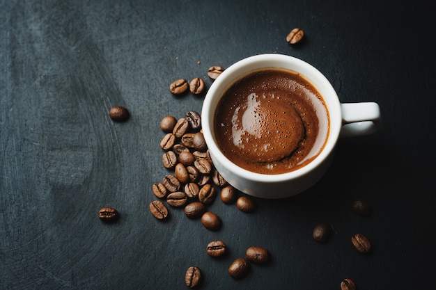 Leckerer dampfender Espresso in einer Tasse mit Kaffeebohnen.