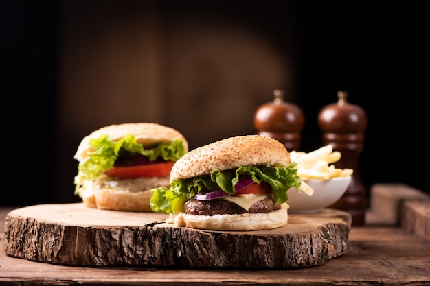 Leckerer gegrillter Rindfleischburger mit Salat, Käse und Zwiebeln, serviert auf Schneidebrett mit Exemplar