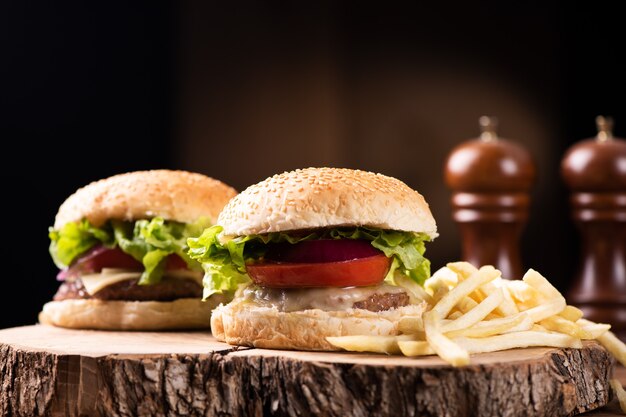 Leckerer gegrillter Rindfleischburger mit Salat, Käse und Zwiebeln, serviert auf Schneidebrett mit Exemplar