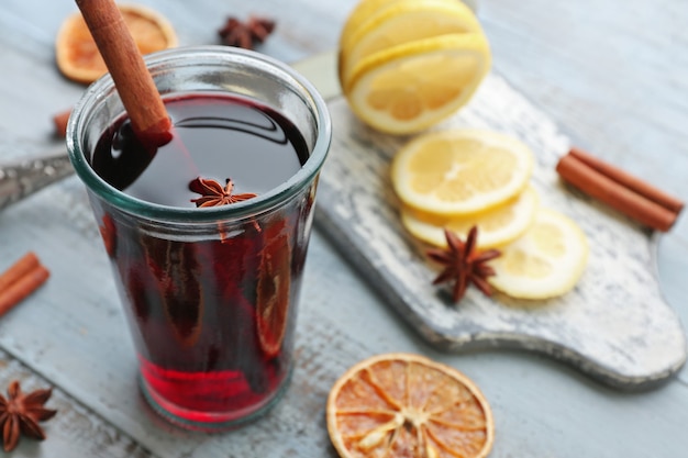 Leckerer Glühwein und Gewürze, auf blauem Holzhintergrund, Nahaufnahme