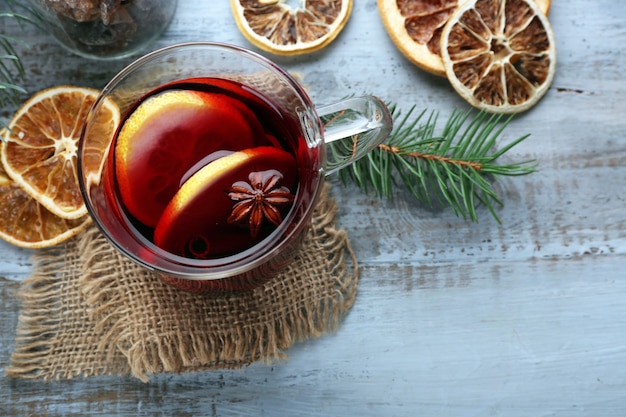 Leckerer Glühwein und Gewürze, auf blauem Holzhintergrund, Nahaufnahme