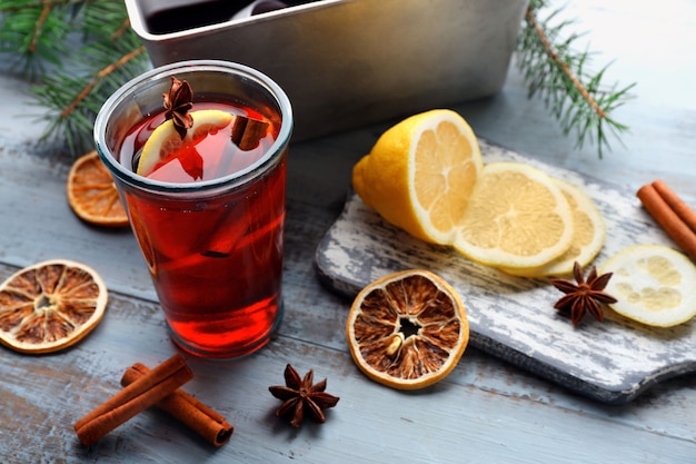 Leckerer Glühwein und Gewürze, auf blauem Holzhintergrund, Nahaufnahme