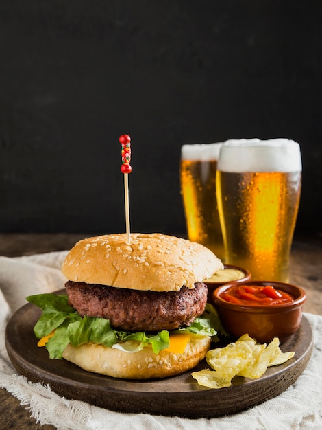 Leckerer Hamburger mit Gläsern Bier und Pommes