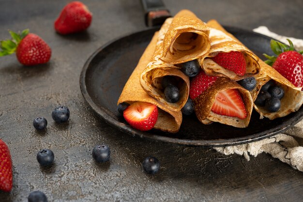 Leckerer hausgemachter rustikaler Pfannkuchen mit Beeren in einer Pfanne auf Holztisch. Maslenitsa-Essen.