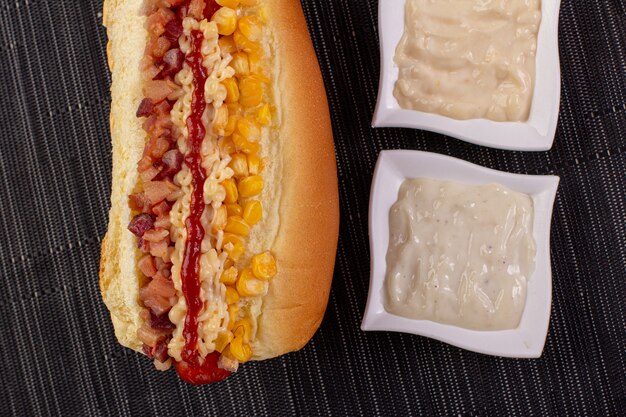 Leckerer Hot Dog mit Zutaten und auf buntem oder hölzernem Hintergrund