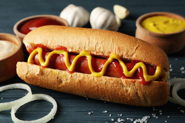 Leckerer Hot Dog und Zutaten auf Holz