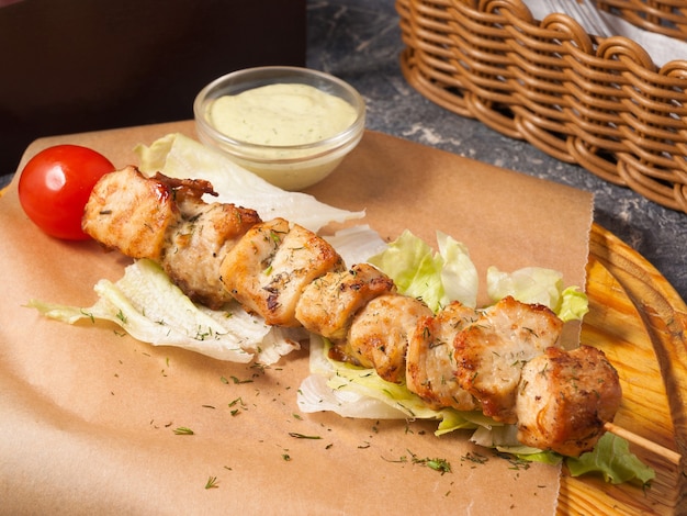 Foto leckerer hühnchen-spieß mit sauce auf einem holzbrett