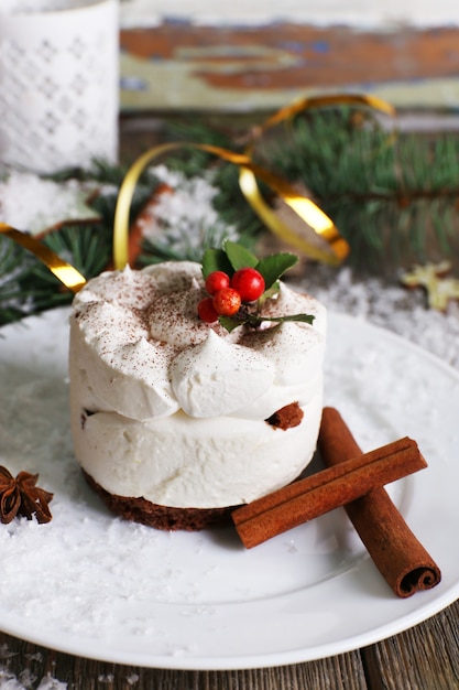 Leckerer Kuchen auf Teller mit Zimt und Sternanis auf Weihnachtsdekorationsoberfläche