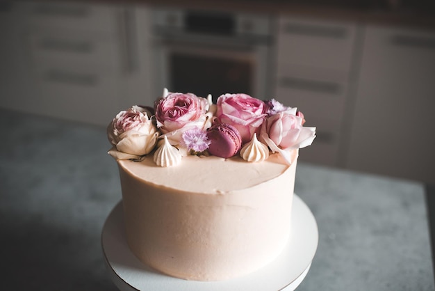 Leckerer Kuchen, dekoriert mit frischen Blumenrosen, die auf dem Küchentisch bleiben