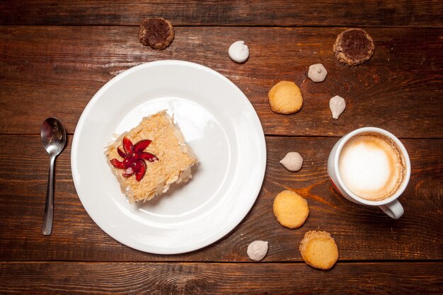 Leckerer Kuchen und Tasse Cappuccino auf Holztisch