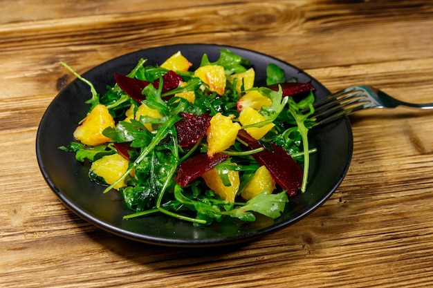 Leckerer Salat aus frischer Rucola Rote Beete und Orangen auf Holztisch Gesundes Essen oder vegetarisches Konzept