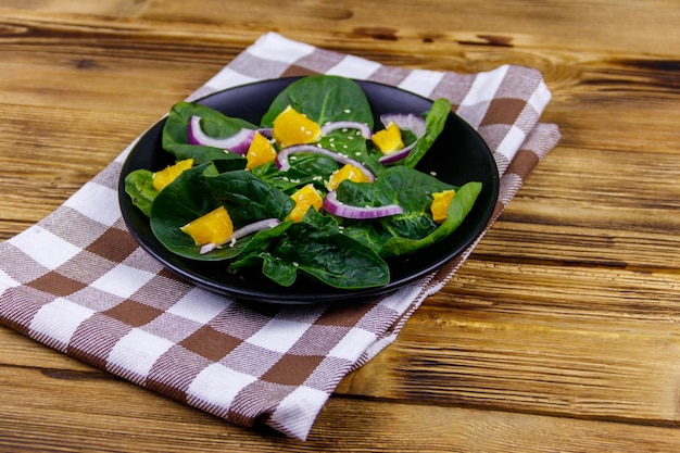 Leckerer Salat mit Spinat, orange, roter Zwiebel und Sesamsamen auf Holztisch Gesundes Essen oder vegetarisches Konzept