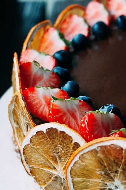 leckerer Schokokuchen dekoriert mit frischen Erdbeeren Heidelbeeren Minze und kandierten Orangen