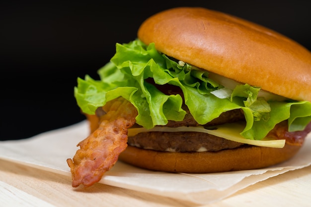 Leckerer Speck und Cheeseburger mit Salat auf einer Papierserviette zum Mitnehmen oder Fast Food in einer Cafeteria