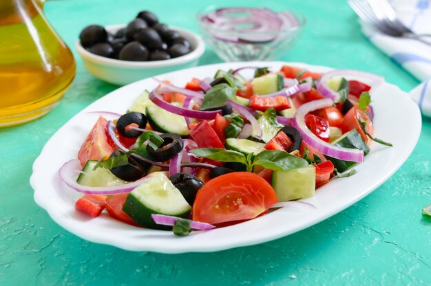 Leckerer veganer Salat aus Tomaten, Gurken, roten Zwiebeln und schwarzen Oliven