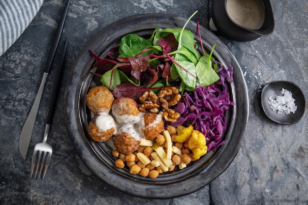 Leckerer veganer vegetarischer Salat mit Kichererbsen, Falafel und Blättern auf Teller serviert.