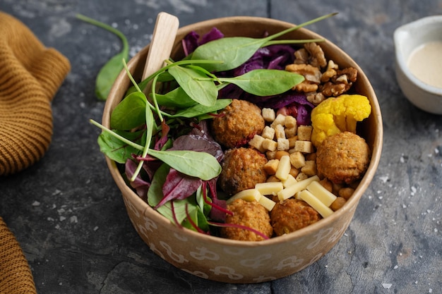 Leckerer veganer vegetarischer Salat mit Kichererbsen, Falafel und Blättern, serviert in einer Papierschale. Gesundes Leben oder Null-Abfall-Konzept