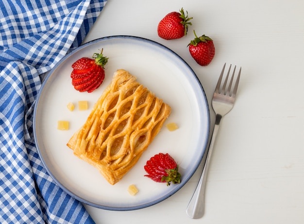 leckerer Waffelkuchen mit Erdbeeren auf weißem Holztisch zum Frühstück